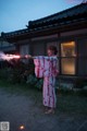 A woman in a kimono holding a sparkler in her hand.