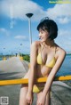 A woman in a yellow bikini standing on a pier.