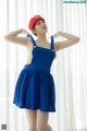 A woman in a blue dress and a red hat posing for a picture.