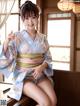 A woman in a blue kimono sitting on a window sill.