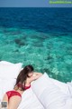 A woman in a red bikini laying on a bed.