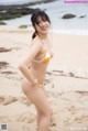 A woman in a bikini standing on a beach.