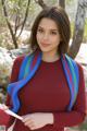 A woman in a red dress holding a blue and green scarf.