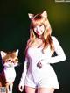 A woman in a white dress standing next to a cat.