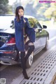 A woman standing next to a car on the side of the road.