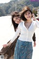 Two young women standing next to each other on a beach.