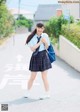 A young woman in a school uniform is walking down the street.